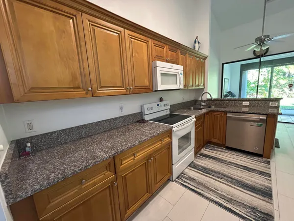 a kitchen with granite countertop a sink stainless steel appliances wooden cabinets and a window