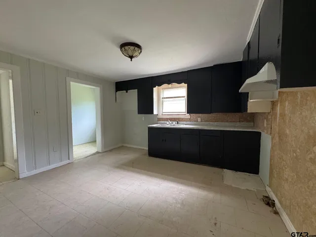a view of an empty room with a kitchen and a window