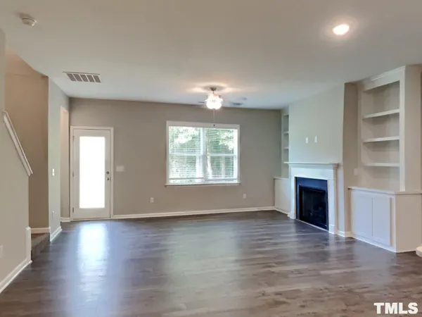 an empty room with wooden floor fireplace and windows