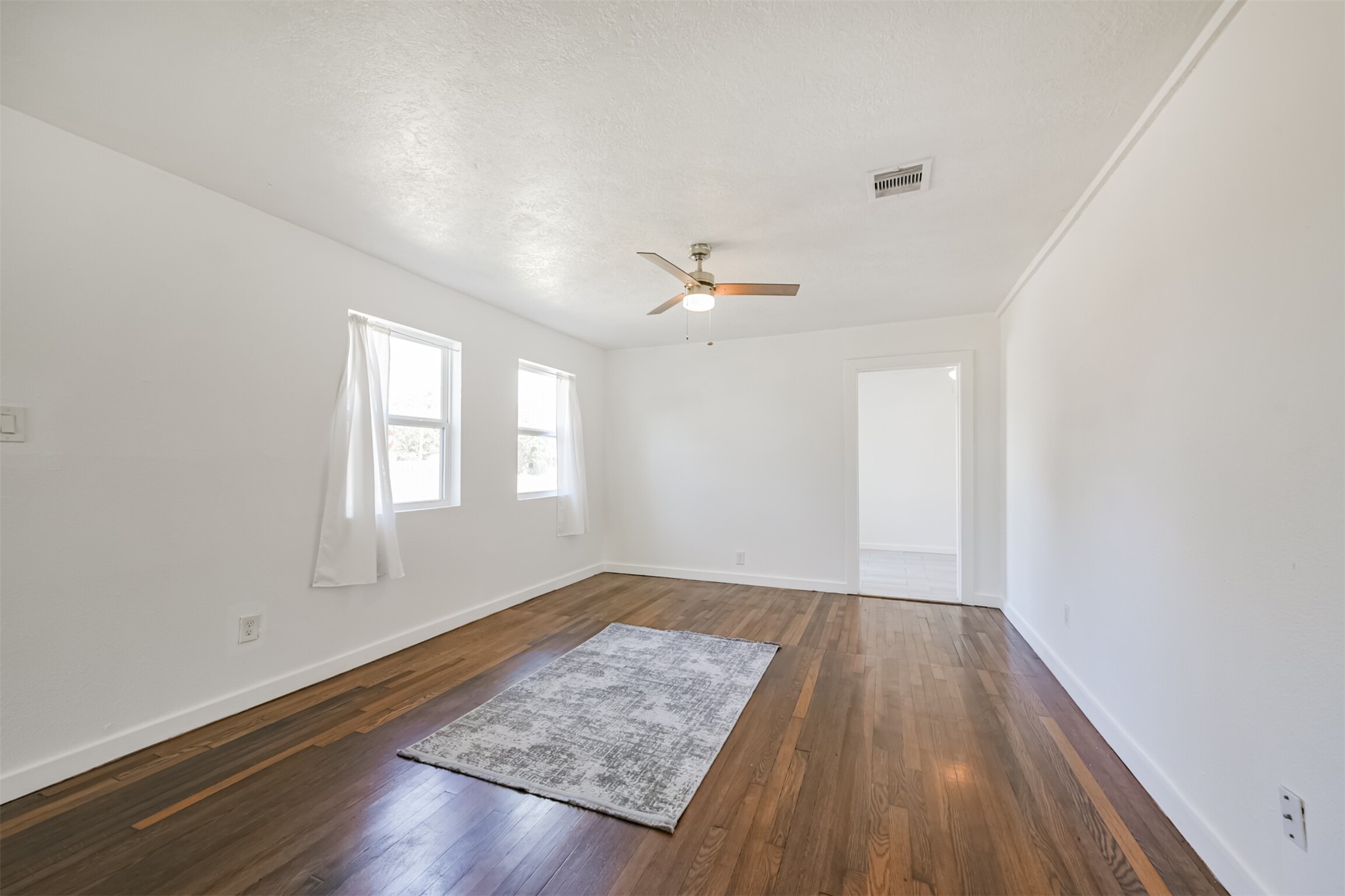 7546 Greendowns Street Houston, TX 77087 - Photo 13 of 33 an empty room with wooden floor and windows