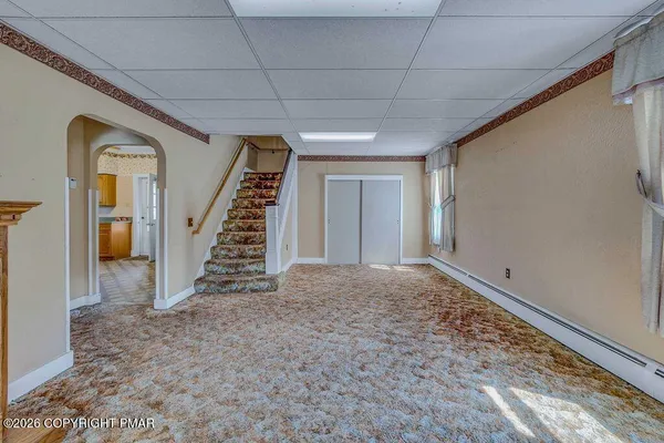 a view of an empty room with stairs and a rug