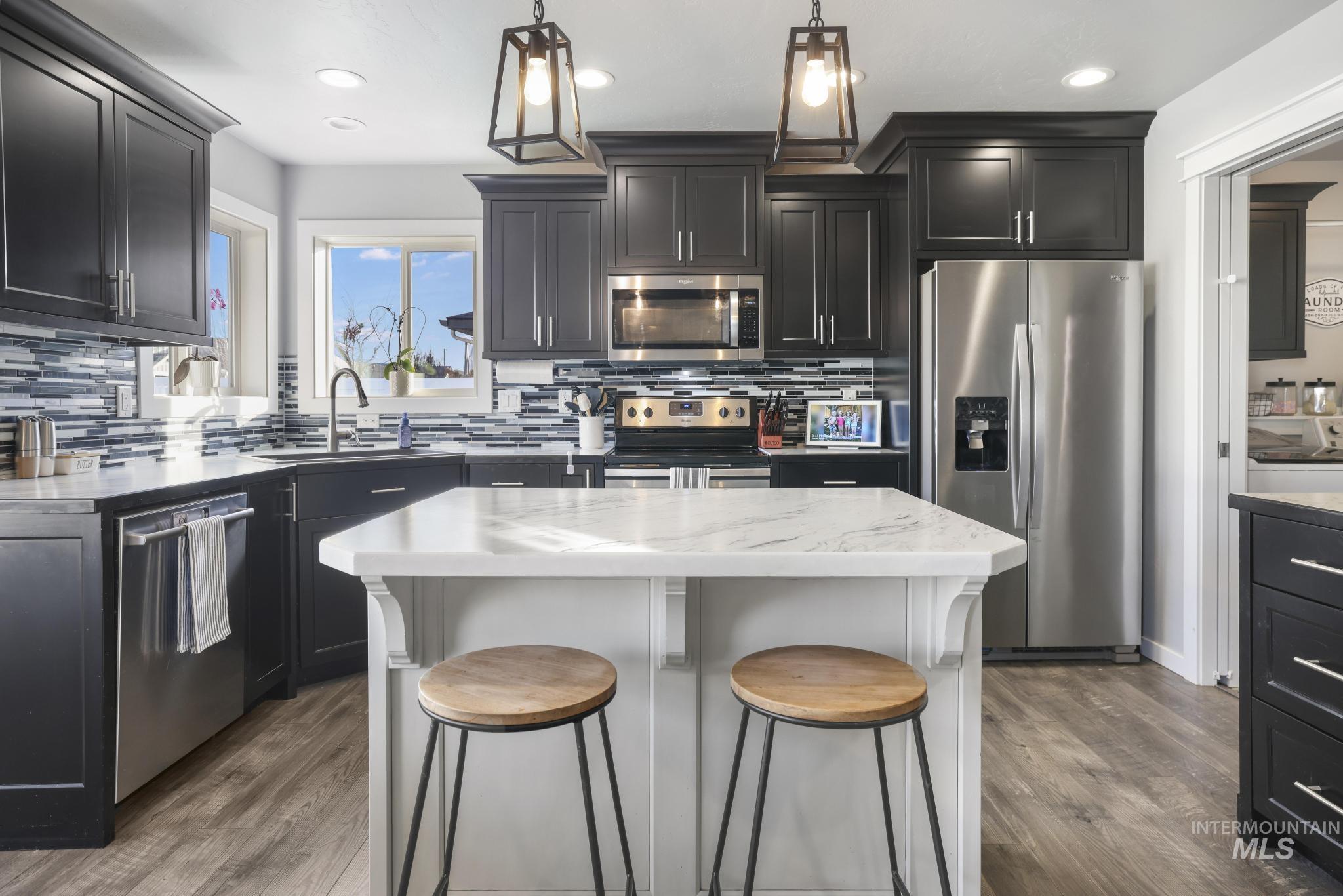 2396 Village Street Twin Falls, ID 83301 - Photo 16 of 44 Kitchen featuring dark cabinetry, appliances with stainless steel finishes, dark wood-style flooring, decorative light fixtures, and recessed lighting