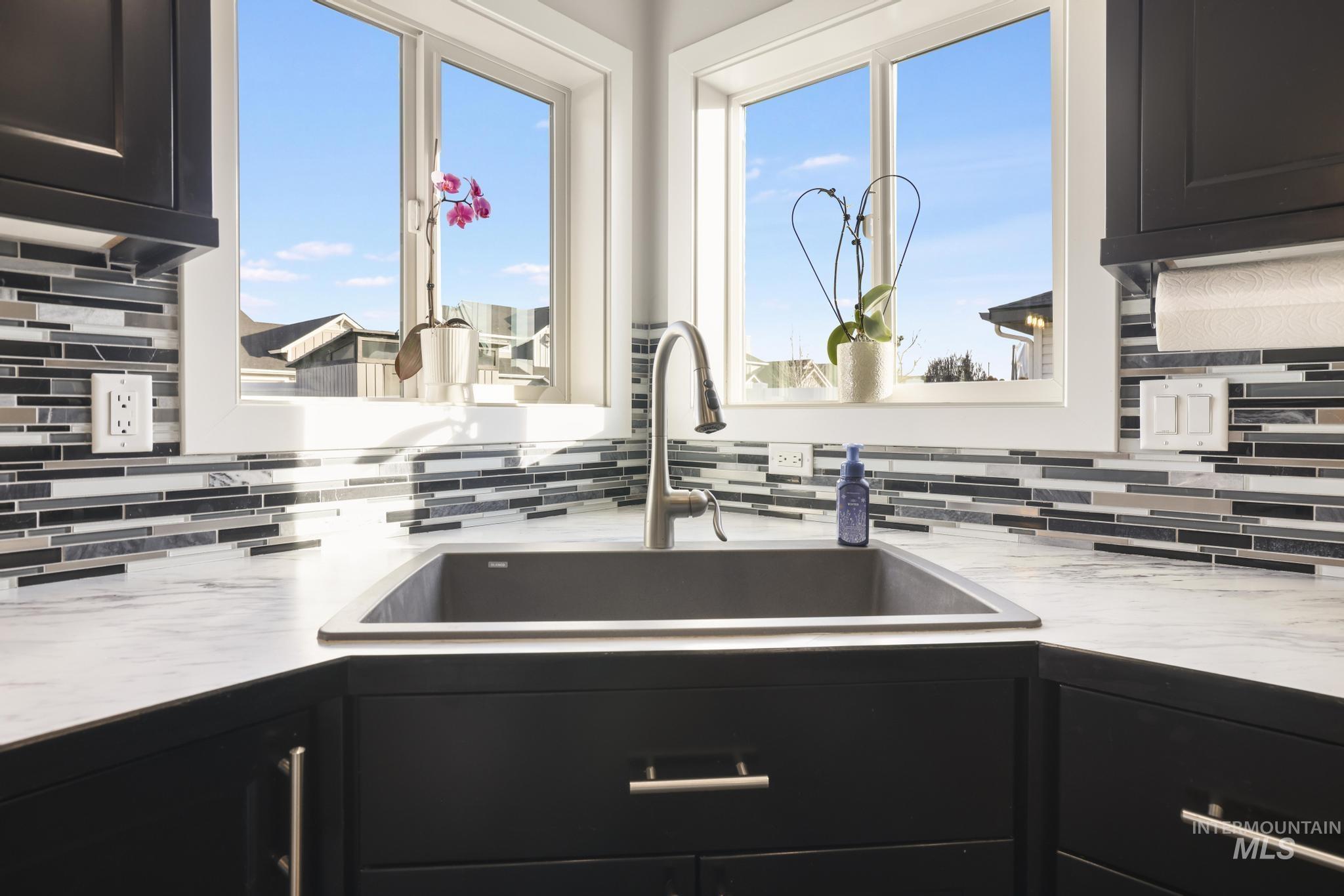 2396 Village Street Twin Falls, ID 83301 - Photo 20 of 44 Kitchen with dark cabinetry, decorative backsplash, and light stone counters