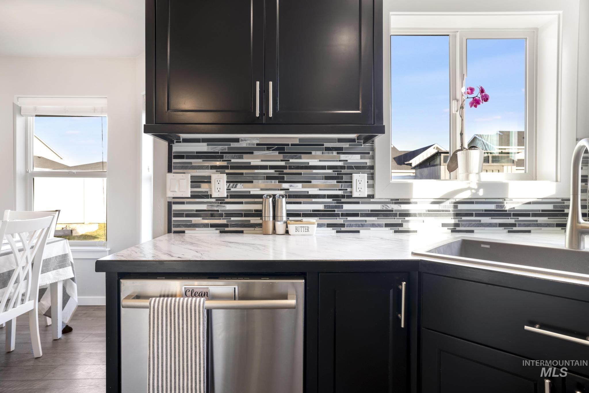 2396 Village Street Twin Falls, ID 83301 - Photo 22 of 44 Kitchen featuring dishwasher, decorative backsplash, dark cabinetry, light stone countertops, and wood finished floors