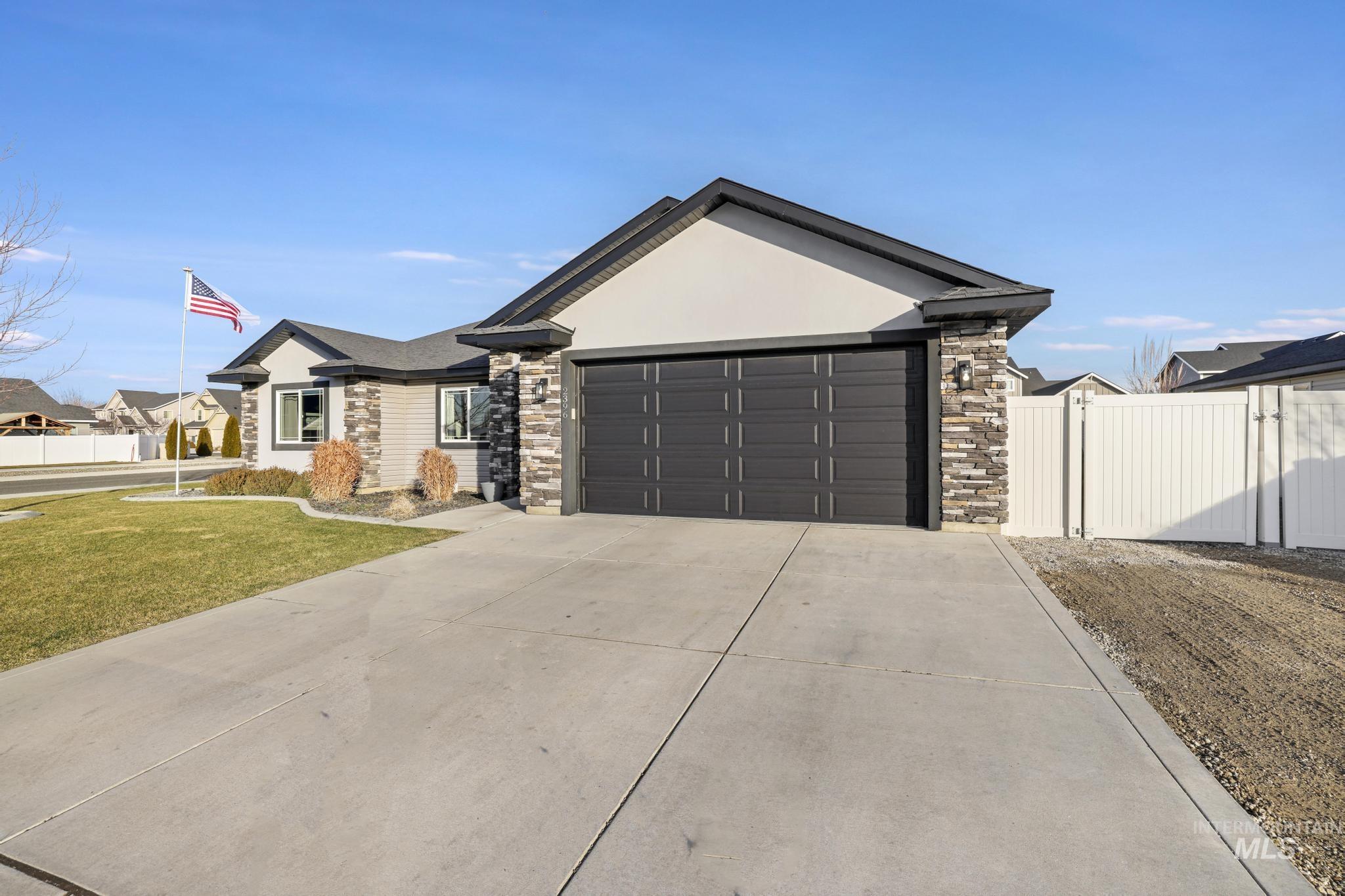 2396 Village Street Twin Falls, ID 83301 - Photo 4 of 44 Ranch-style home featuring stone siding, driveway, a garage, stucco siding, and a gate