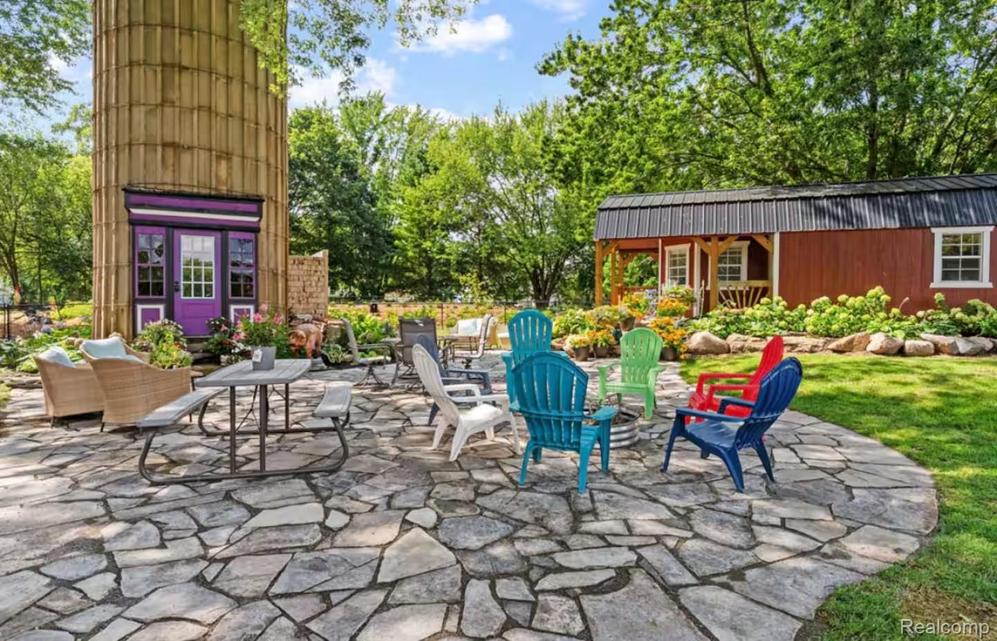 4567 North Seymour Road Flushing, MI 48433 - Photo 4 of 43 Expansive flagstone patio area with a central fire pit, surrounded by a manicured lawn and mature trees