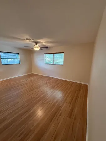 an empty room with wooden floor and windows