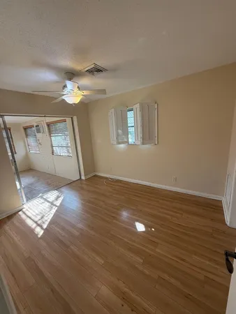 a view of empty room with wooden floor and fan
