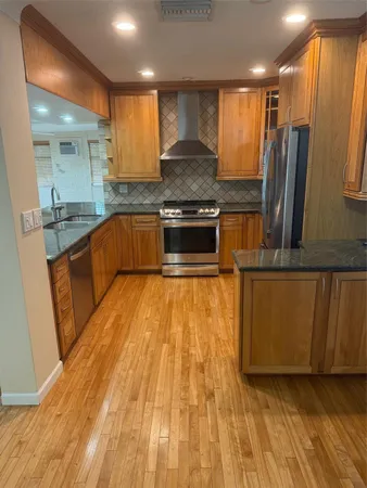 a large kitchen with stainless steel appliances wooden floors and wooden cabinets