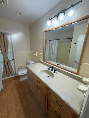 a bathroom with a granite countertop sink a toilet and a mirror