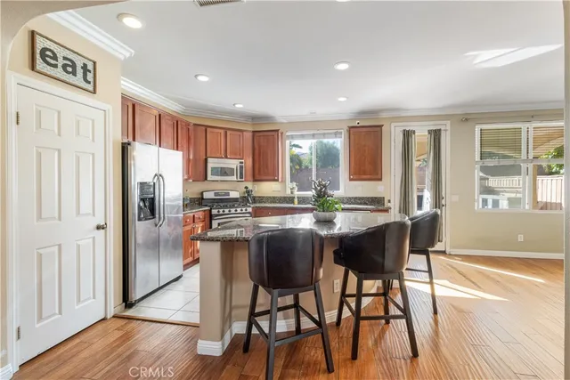 a kitchen with stainless steel appliances granite countertop a refrigerator a stove a sink and white cabinets with wooden floor