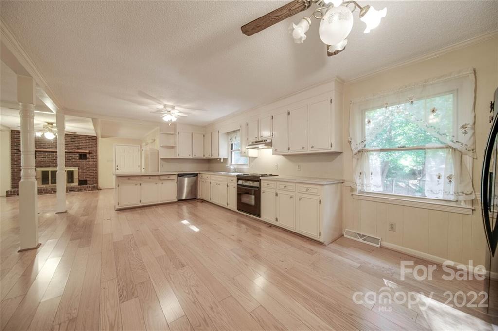 699 Bailey Road Lancaster, SC 29720 - Photo 8 of 43 a large white kitchen with kitchen island a stove a sink dishwasher and white cabinets with wooden floor