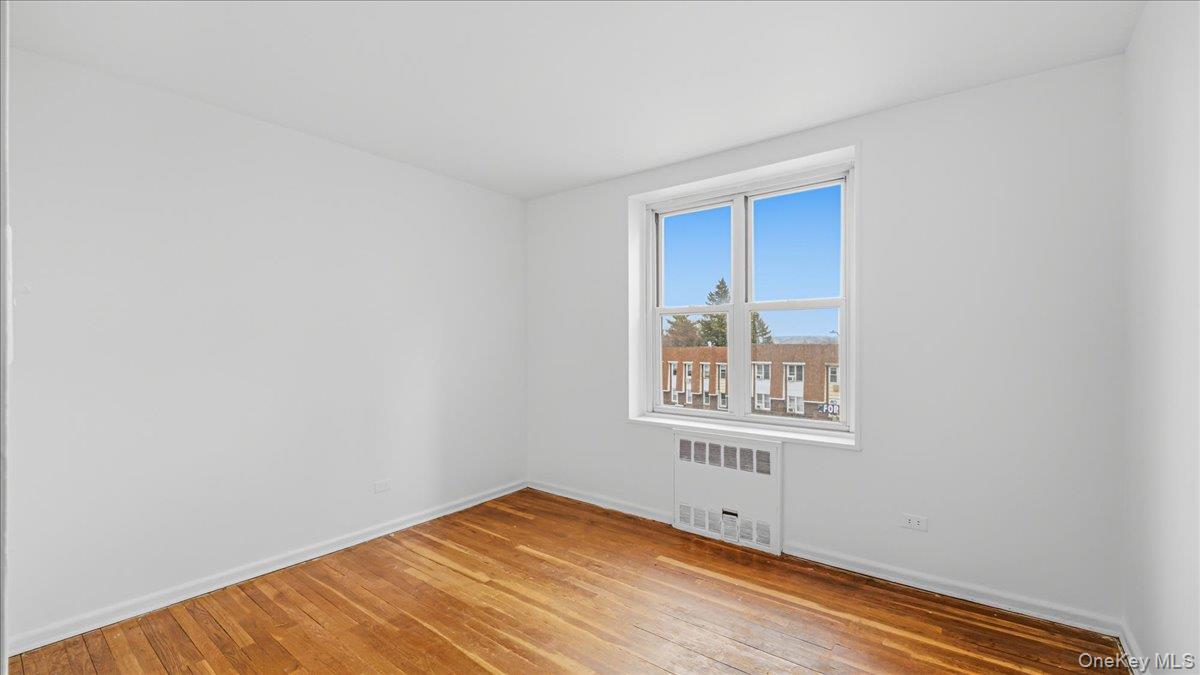 210-15 23rd Avenue, Unit 3F Queens, NY 11360 - Photo 17 of 24 a view of an empty room with wooden floor and a window