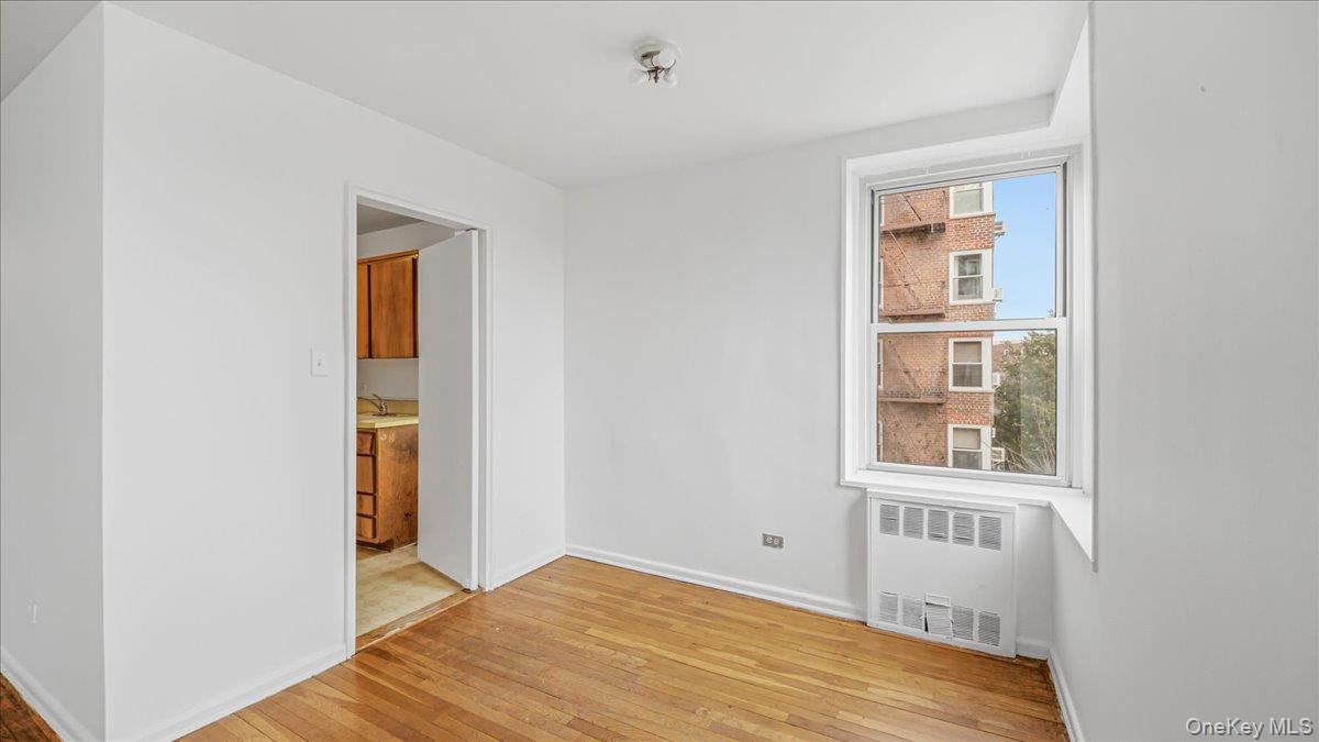 210-15 23rd Avenue, Unit 3F Queens, NY 11360 - Photo 10 of 24 a view of an empty room with wooden floor and a window