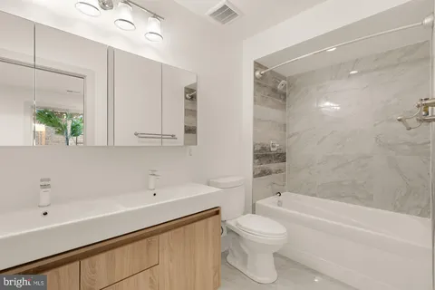 a bathroom with a bathtub shower sink vanity mirror and toilet