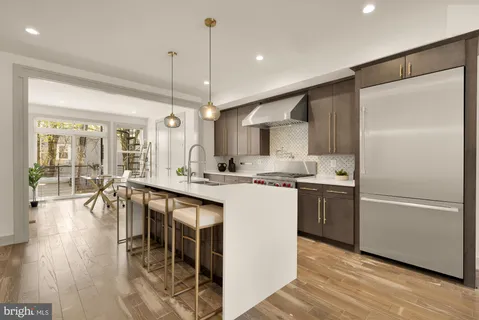 a kitchen with stainless steel appliances granite countertop a refrigerator a sink a stove and a wooden floors