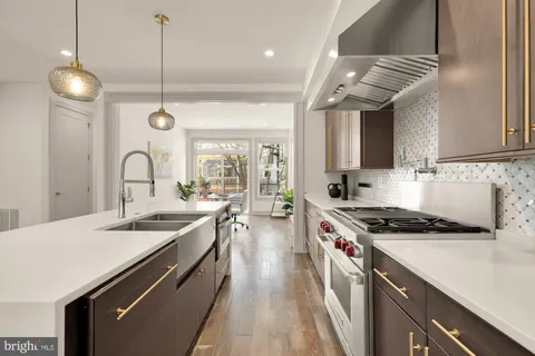 a kitchen with kitchen island stainless steel appliances a sink a stove and a wooden floors
