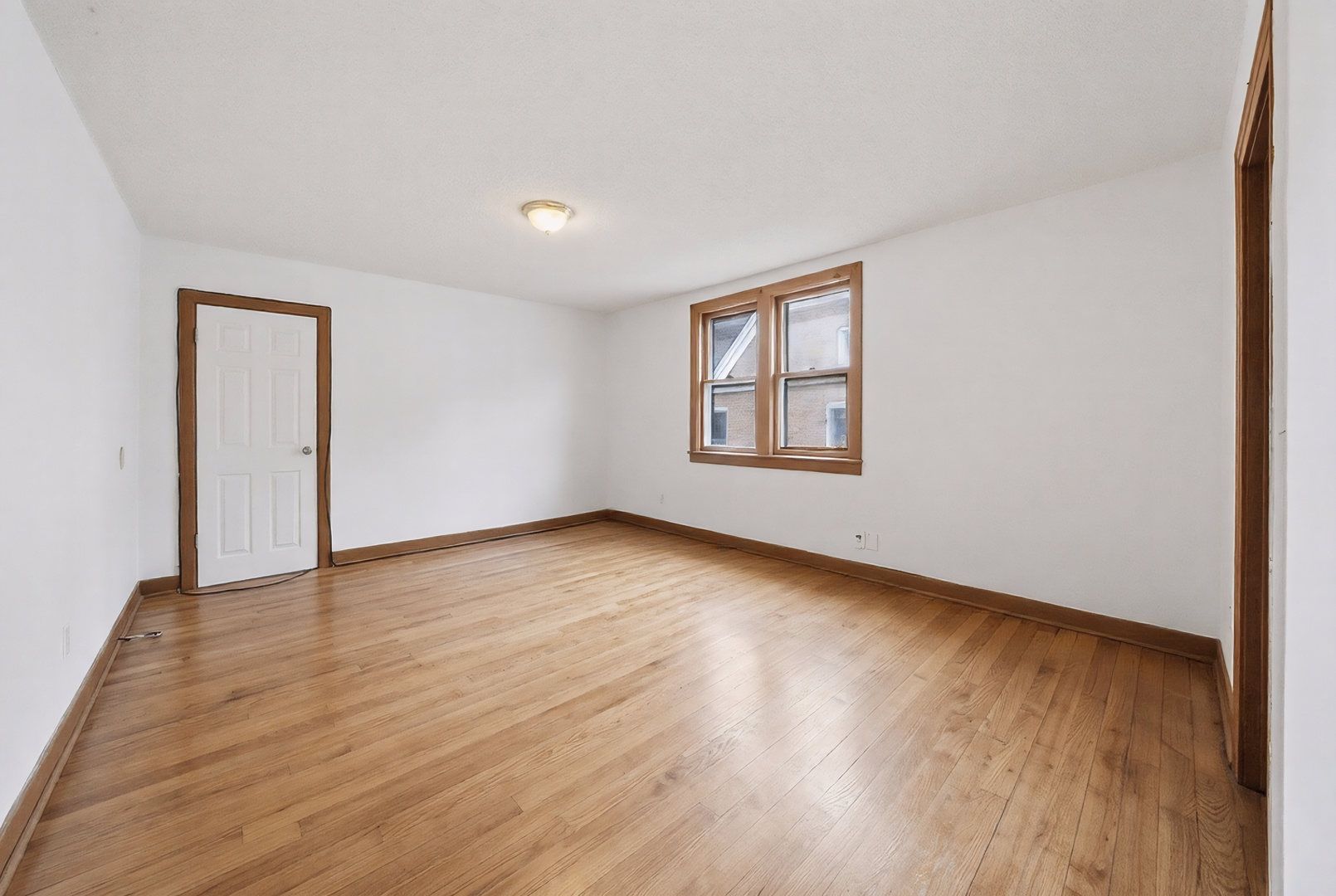 11735 South Indiana Avenue Chicago, IL 60628 - Photo 13 of 26 an empty room with wooden floor and windows