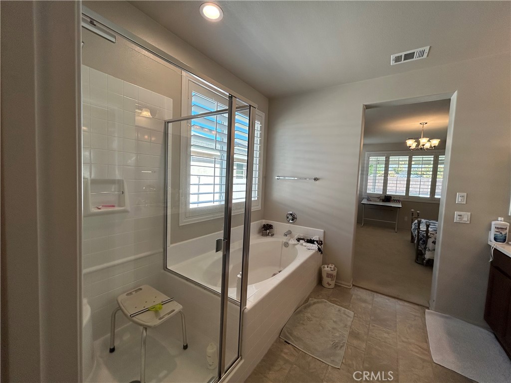 30099 Whembly Circle Menifee, CA 92584 - Photo 14 of 42 a bathroom with a tub a mirror and shower