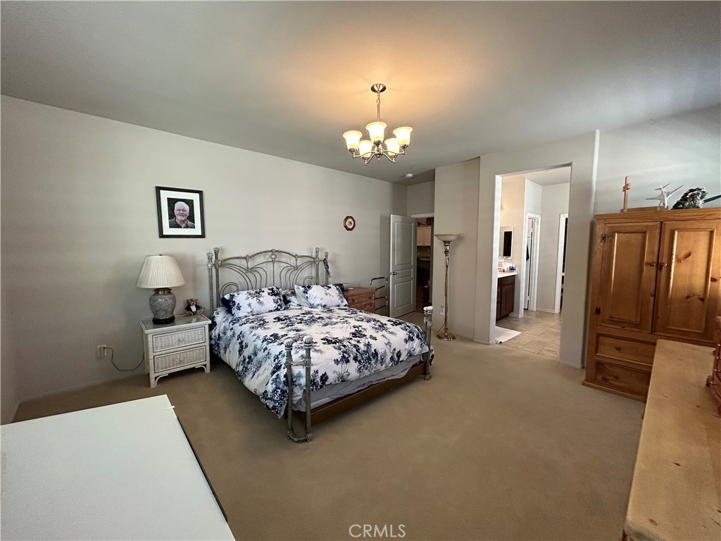 30099 Whembly Circle Menifee, CA 92584 - Photo 10 of 42 a spacious bedroom with a bed and a chandelier