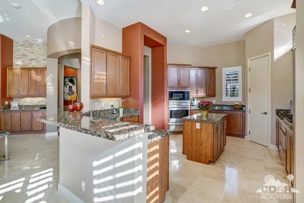 a kitchen with stainless steel appliances kitchen island granite countertop a refrigerator a stove and a sink