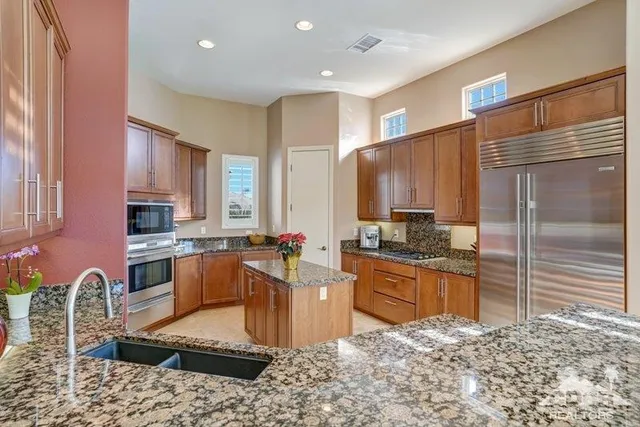 a large kitchen with granite countertop a sink refrigerator and cabinets