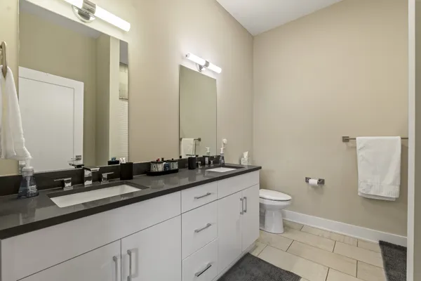a bathroom with a double vanity sink a toilet and a mirror
