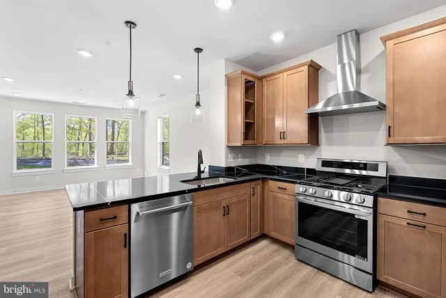 a kitchen with stainless steel appliances granite countertop a sink a stove and a wooden floors