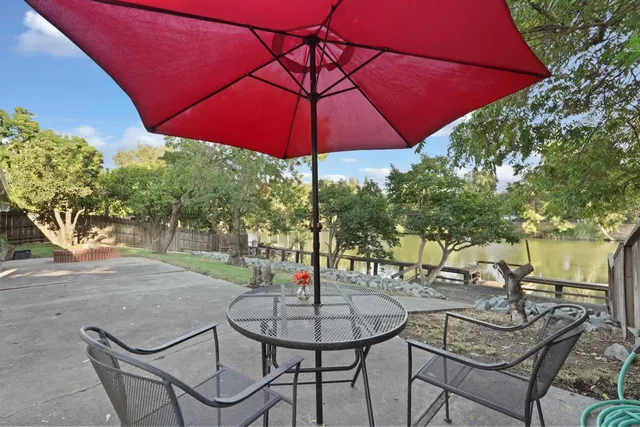 a backyard of a house with table and chairs under an umbrella