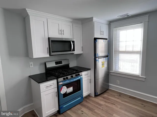 a kitchen with stainless steel appliances white cabinets a stove a microwave and a refrigerator
