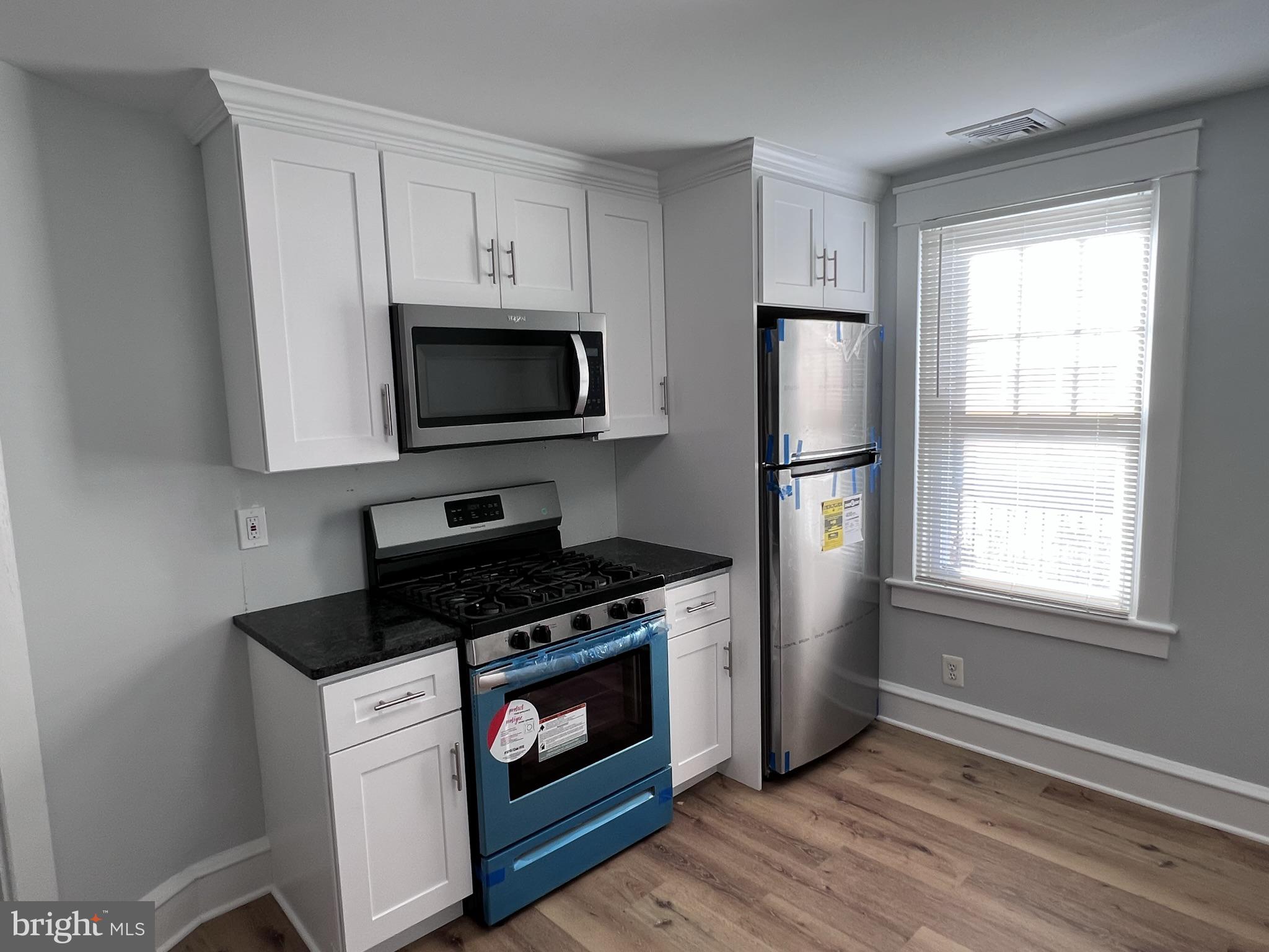 6 Montgomery Avenue, Unit 2 Glenside, PA 19038 - Photo 7 of 27 a kitchen with stainless steel appliances white cabinets a stove a microwave and a refrigerator