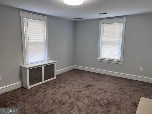 a view of an empty room with a window and a kitchen