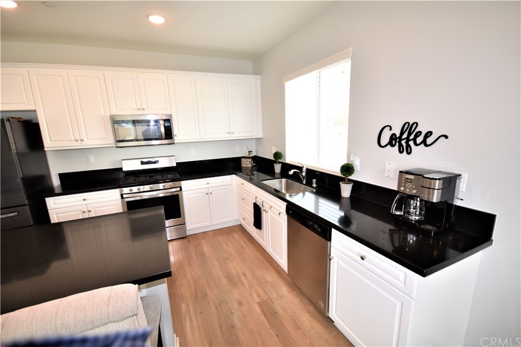 581 Poo'ish Avenue San Jacinto, CA 92582 - Photo 12 of 32 a kitchen with granite countertop a sink a stove top oven and cabinetry