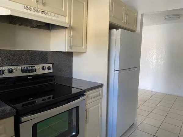 a kitchen with stainless steel appliances granite countertop a sink and a white cabinets with wooden floor