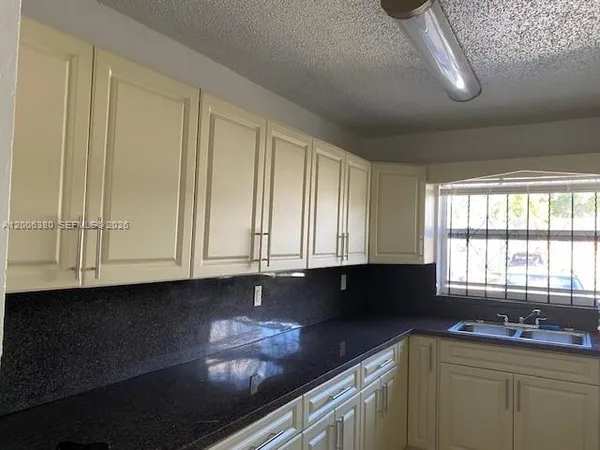 a kitchen with granite countertop white cabinets sink and stainless steel appliances