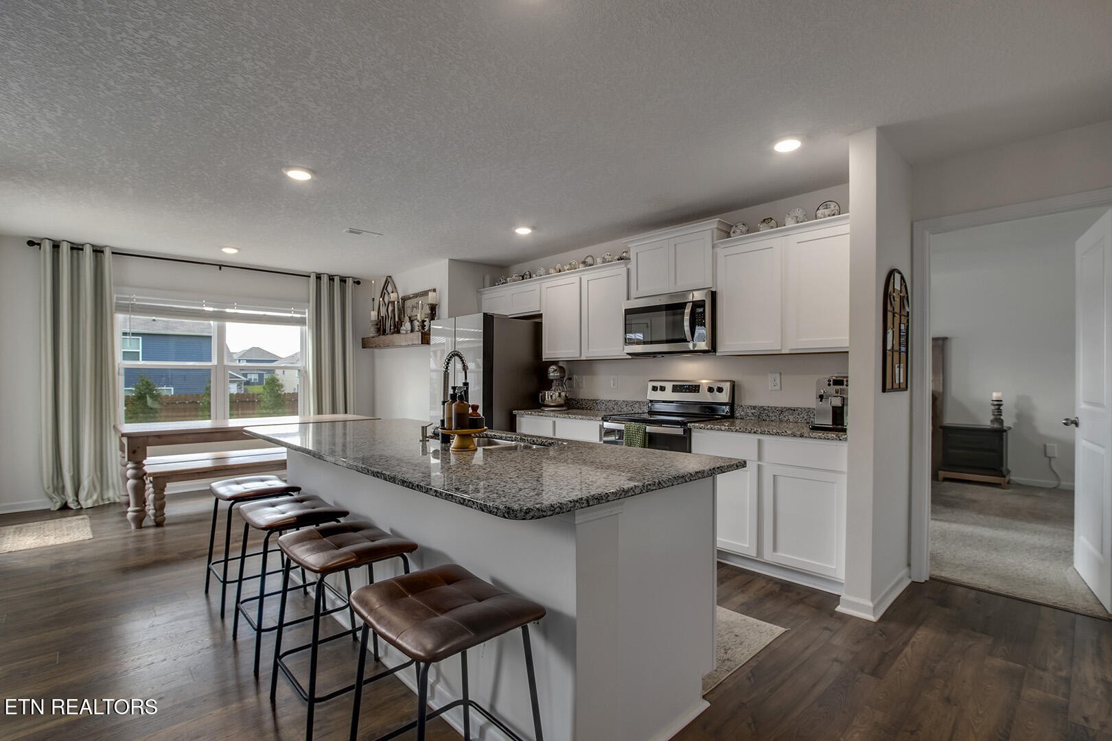 7519 Game Bird Street Corryton, TN 37721 - Photo 17 of 50 a kitchen with stainless steel appliances granite countertop a stove top oven a sink dishwasher a dining table and chairs with wooden floor