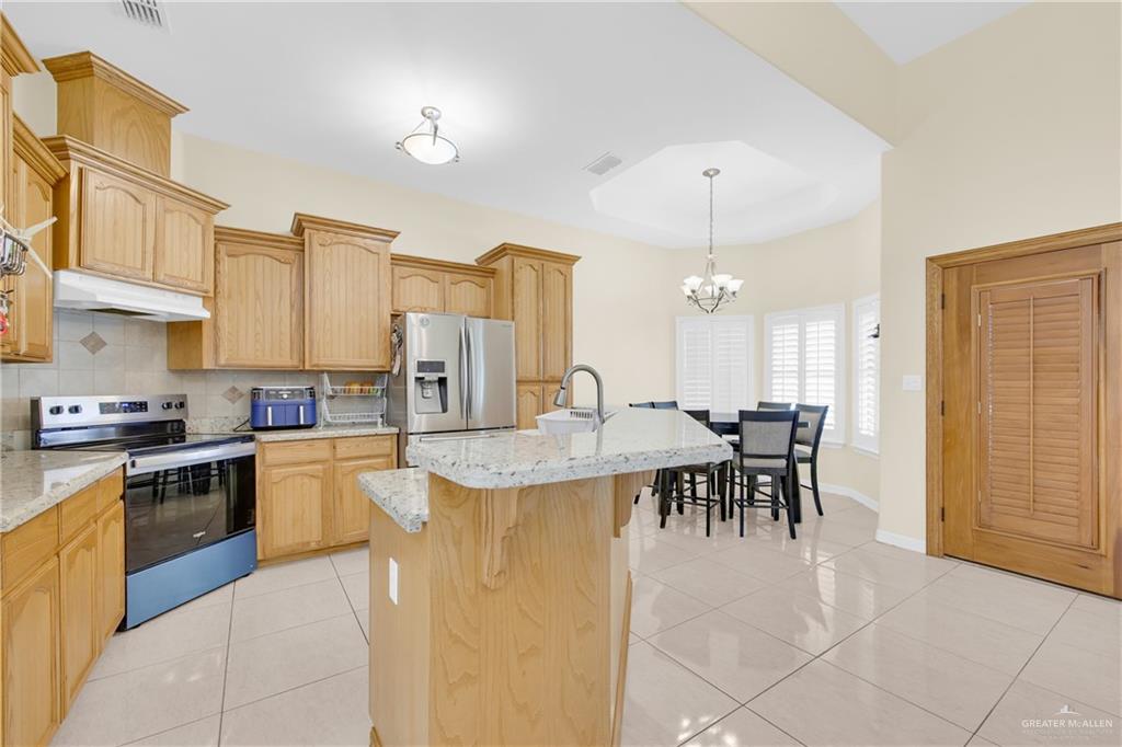 305 North 15th Street Hidalgo, TX 78557 - Photo 11 of 28 a kitchen with kitchen island a dining table chairs stainless steel appliances and cabinets
