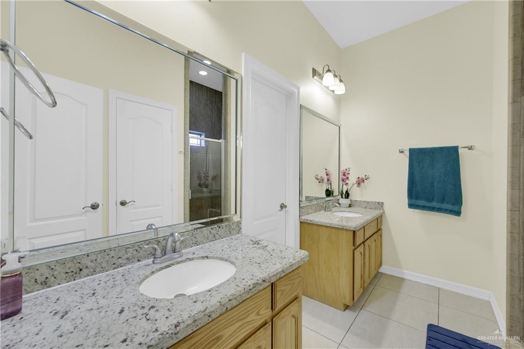 305 North 15th Street Hidalgo, TX 78557 - Photo 16 of 28 a bathroom with a granite countertop sink a mirror and a shower