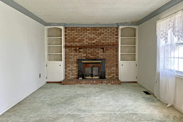 an empty room with windows and fireplace