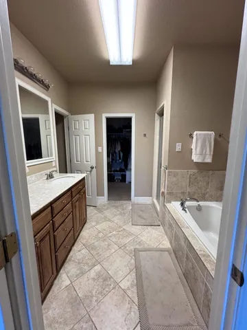 a spacious bathroom with a tub sink and mirror