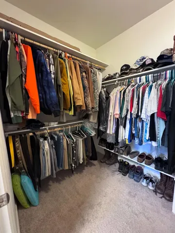 a view of walk in closet with clothes and shoes