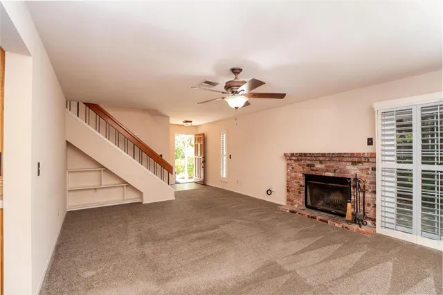 a view of an empty room with staircase and fireplace