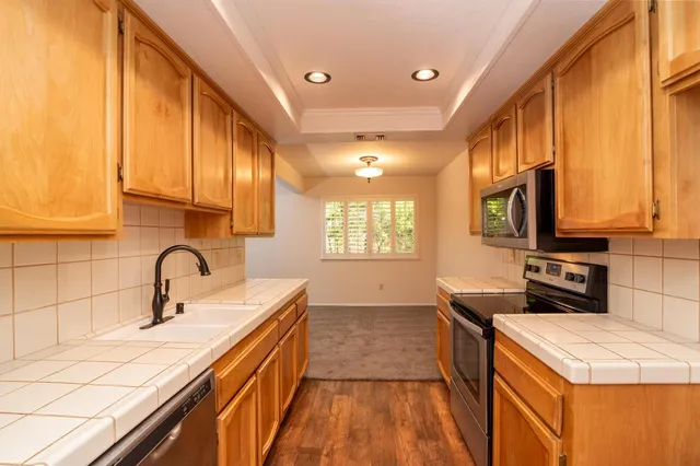 a kitchen with a sink a counter top space stainless steel appliances and cabinets