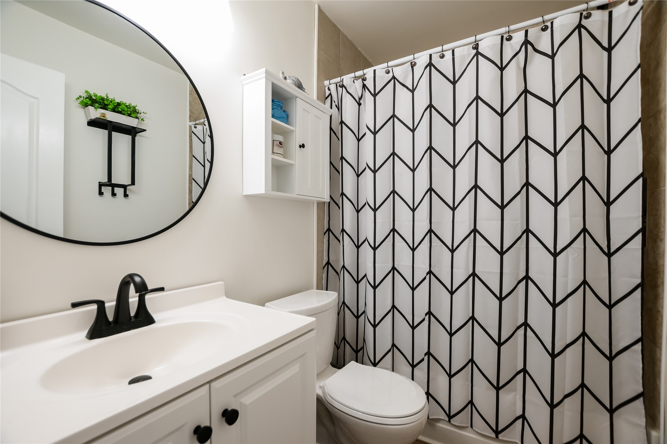 4702 Crest Oak Road Austin, TX 78744 - Photo 13 of 20 Bathroom featuring a white vanity with integrated sink, black faucet, and round black-framed mirror