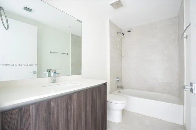 a bathroom with a bathtub shower sink mirror and toilet