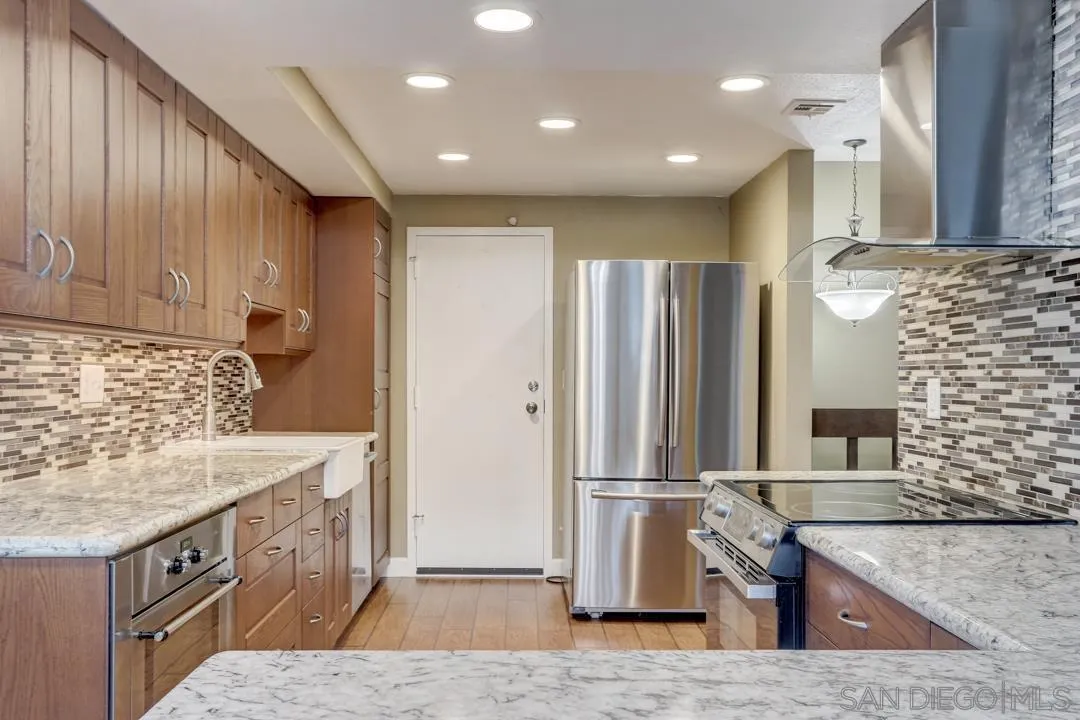 6395 Rancho Mission Road, Unit 15 San Diego, CA 92108 - Photo 4 of 21 a kitchen with kitchen island granite countertop wooden cabinets and a stainless steel appliances
