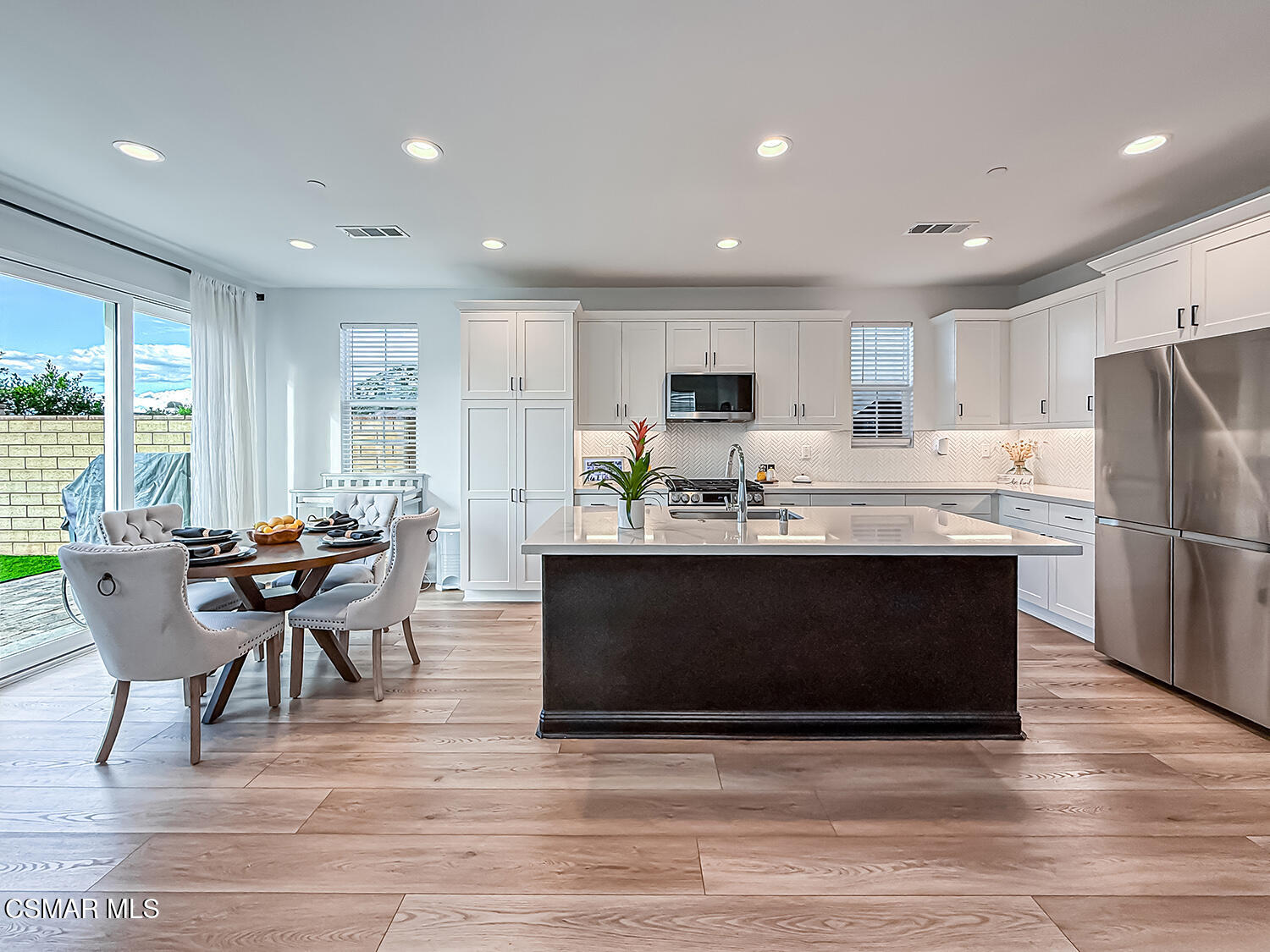 335 Fraser Point Camarillo, CA 93012 - Photo 21 of 85 a kitchen with stainless steel appliances granite countertop a stove a refrigerator a microwave a dining table and chairs with wooden floor