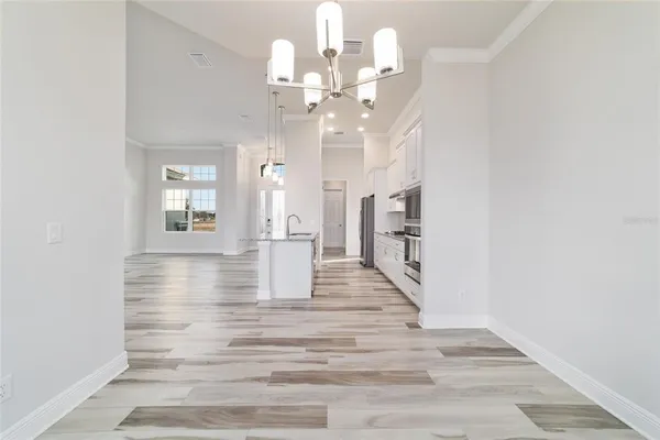 a view of a hallway with wooden floor and chandelier