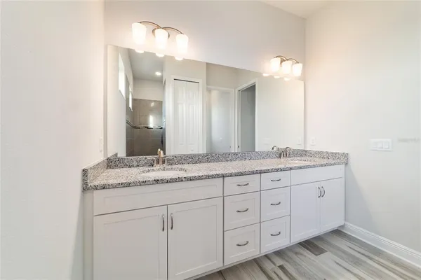 a bathroom with a granite countertop double vanity sink and a mirror
