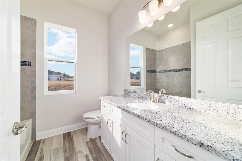 1499 East Pegasus Lane Inverness, FL 34453 - Photo 34 of 46 a bathroom with a granite countertop sink a toilet and a mirror